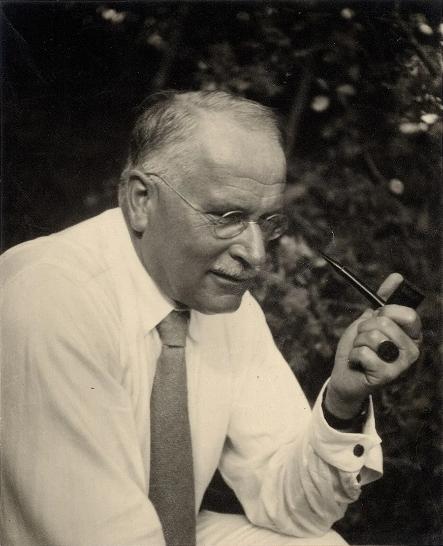 Black-and-white portrait of Carl Gustav Jung in glasses, holding a pipe